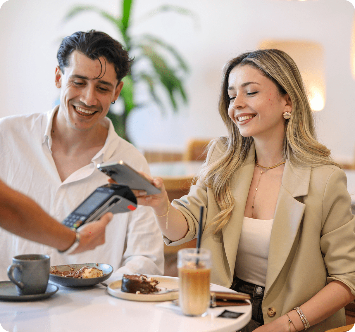 Couple paying with phone at café.