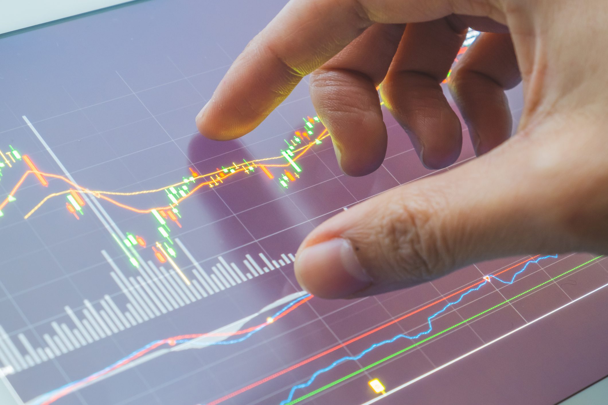 Hand interacting with stock market graph display.
