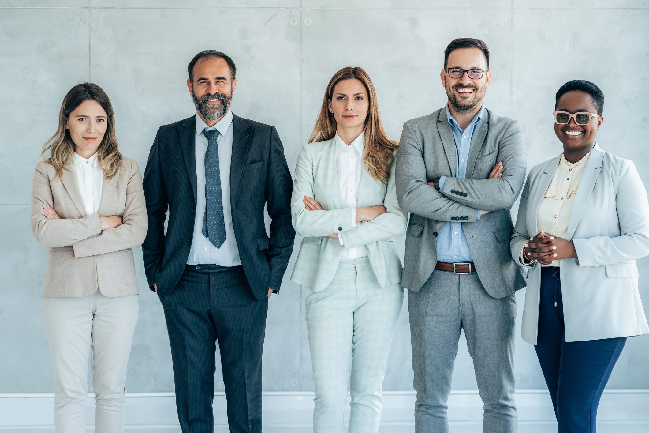 Group of five professionals standing confidently.