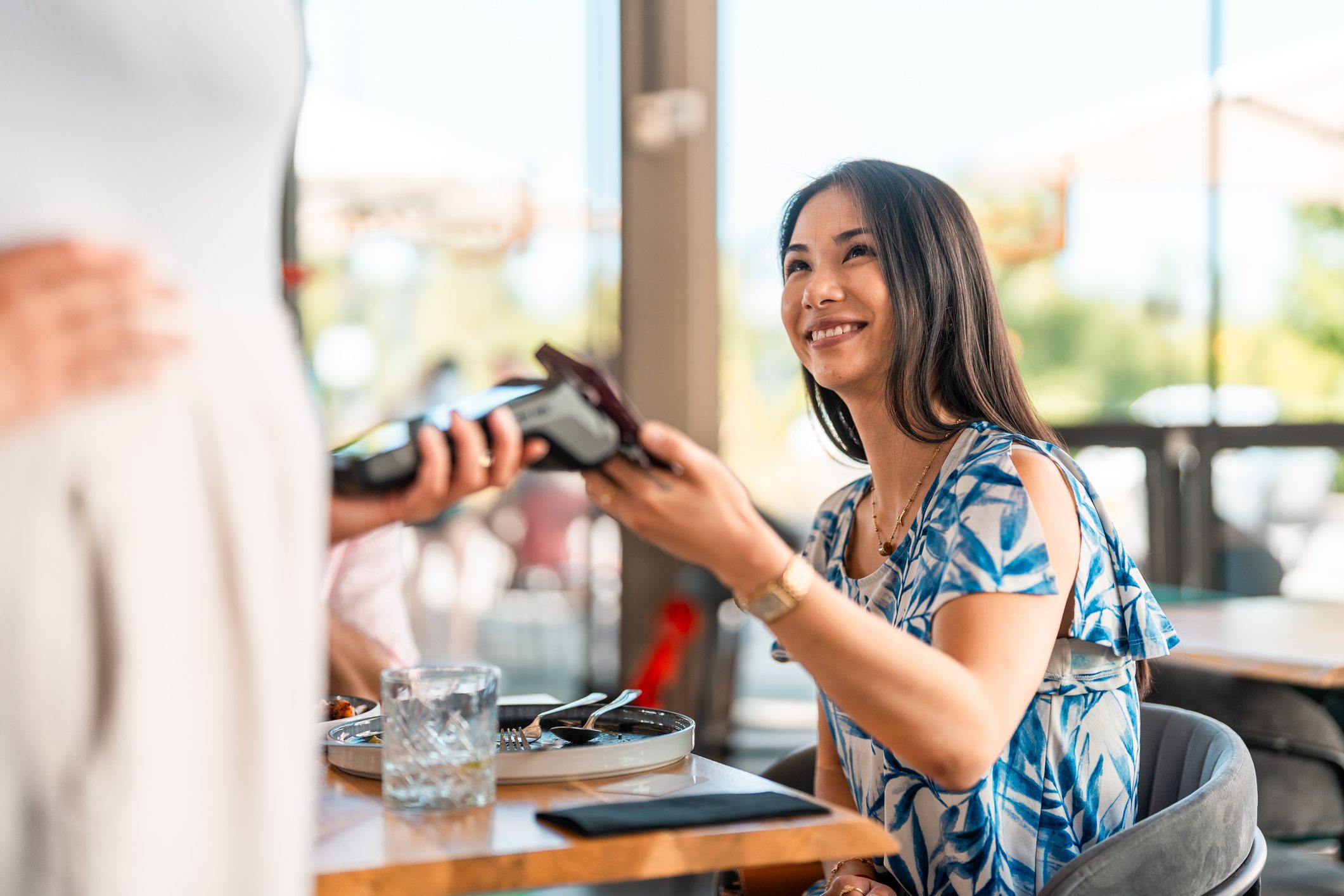 Woman paying at restaurant with card reader.