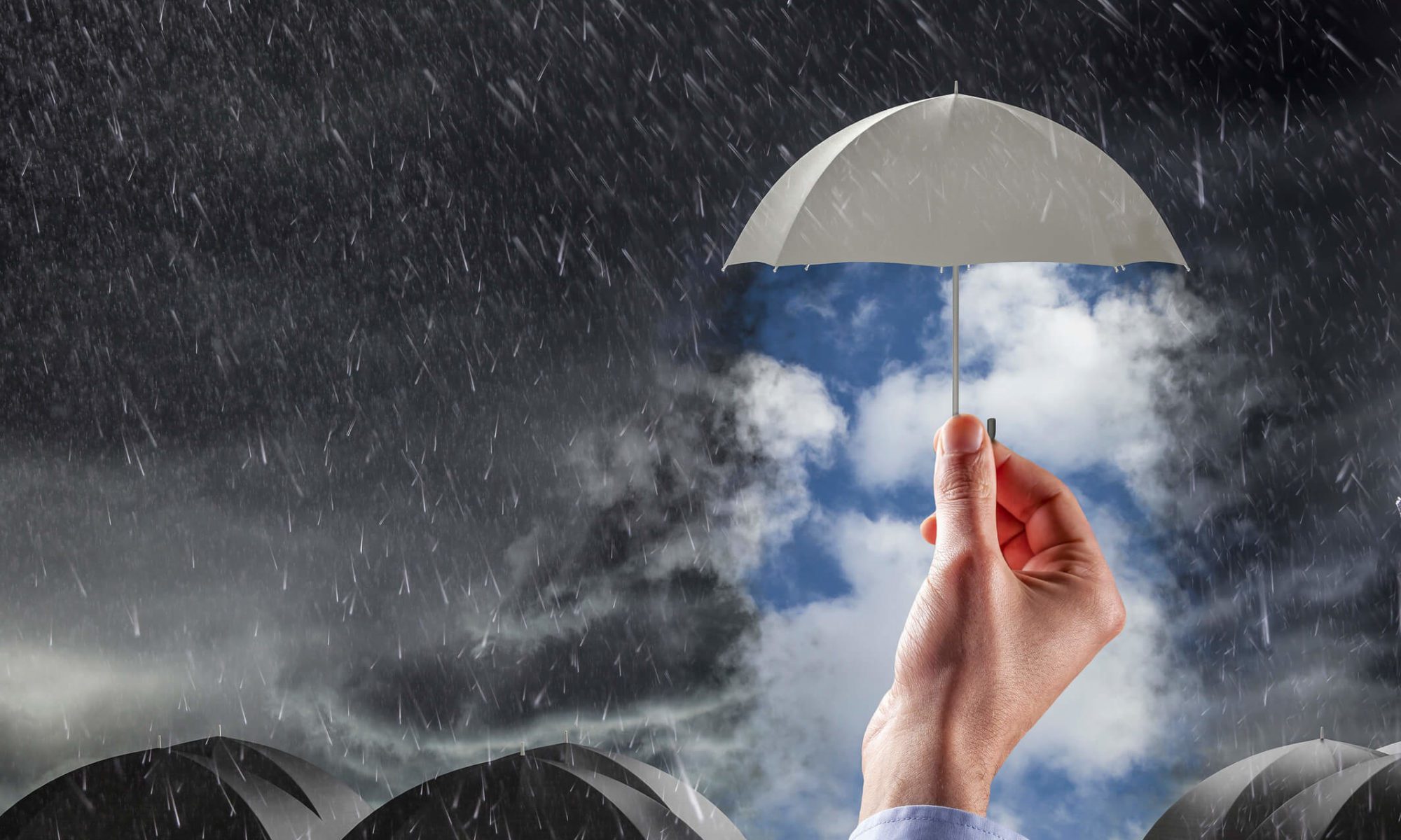 Hand holding umbrella under rainy sky.
