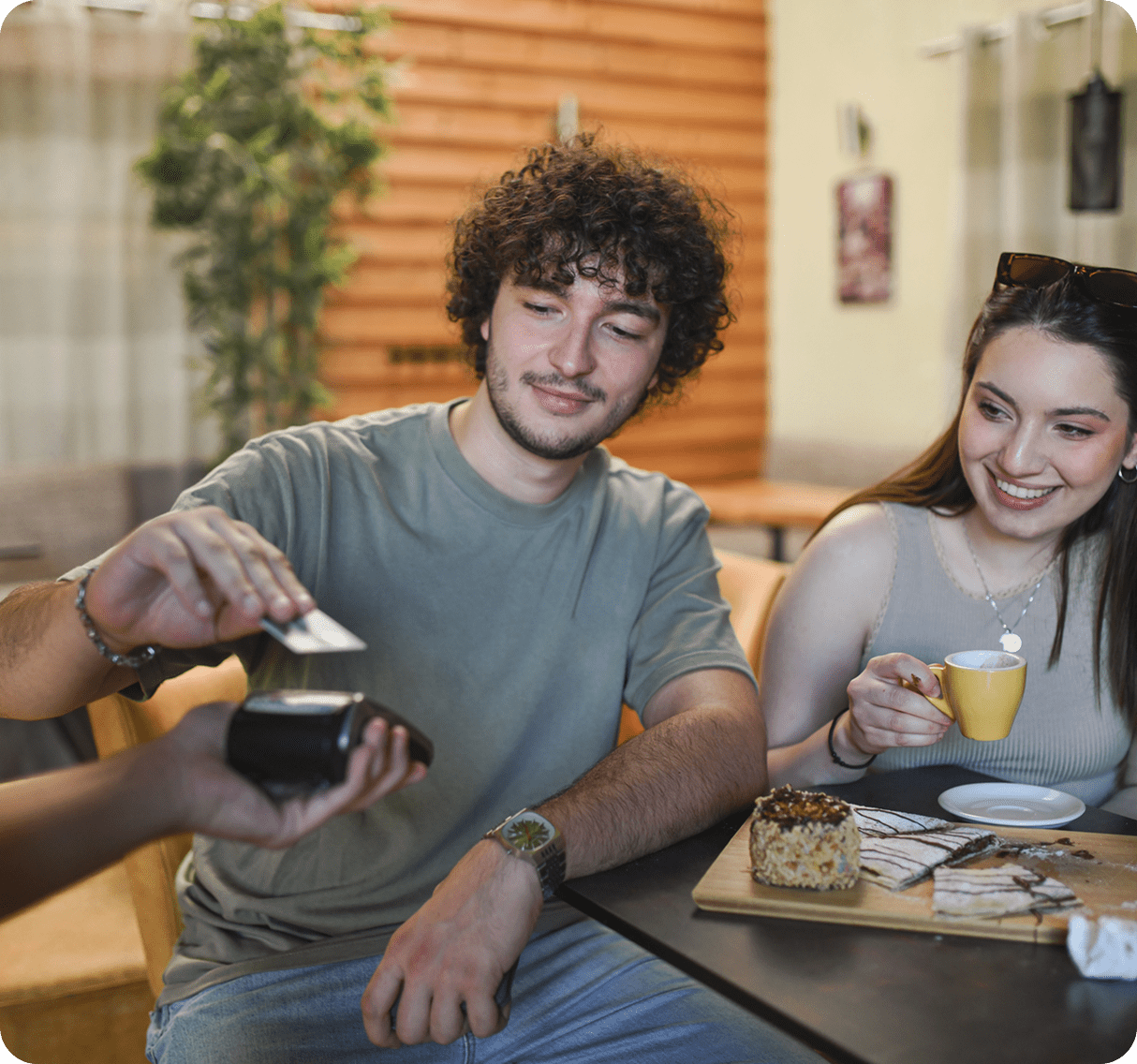Man paying with card at cafe table.