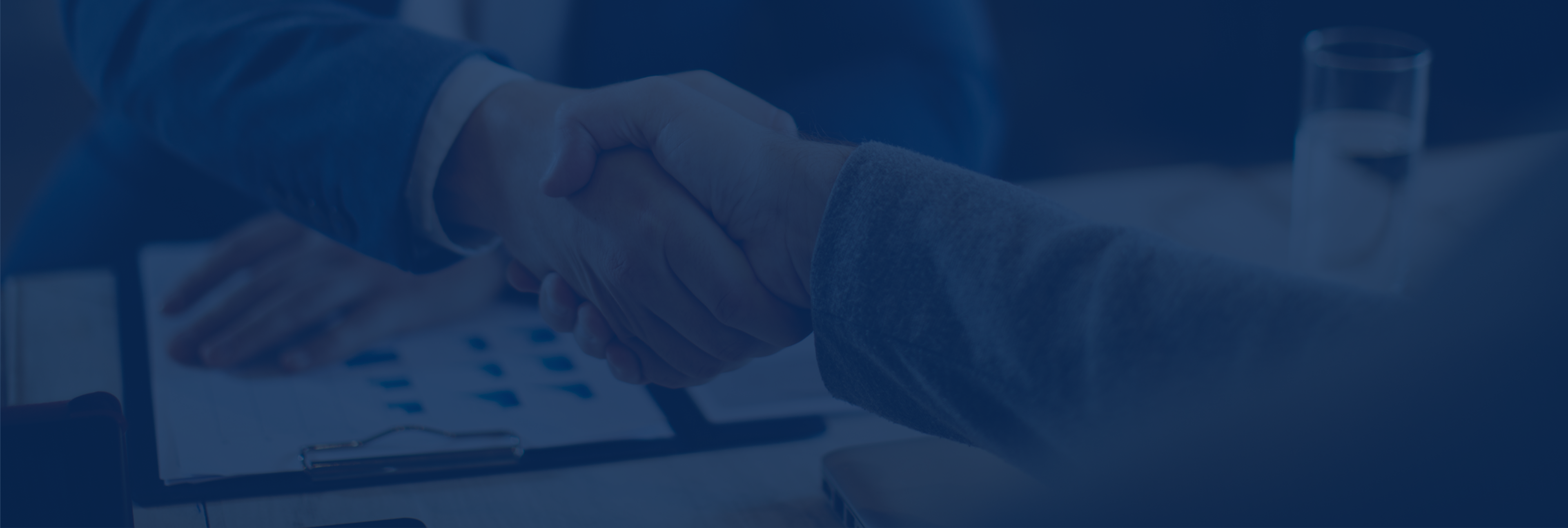 Handshake over business document on table.